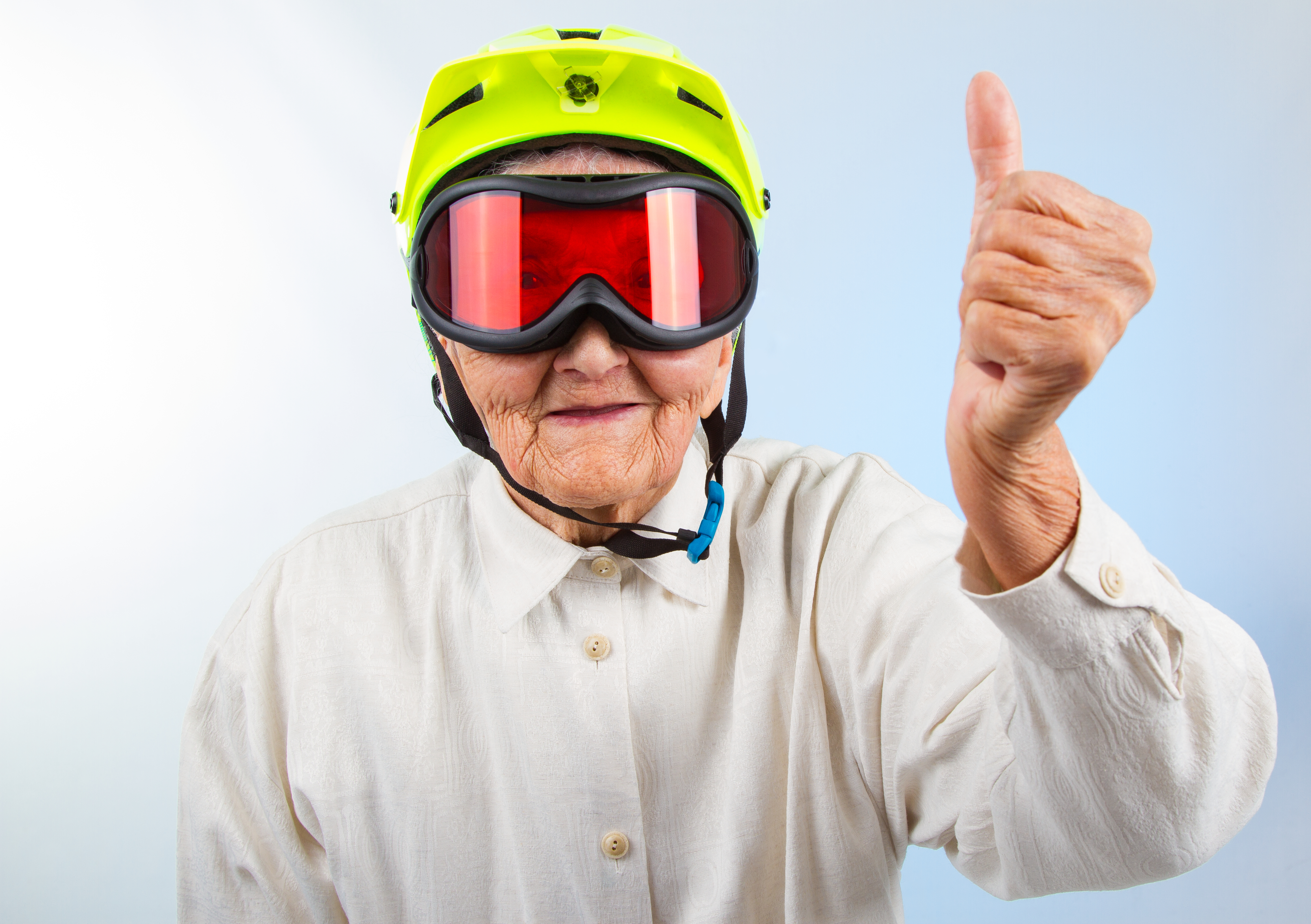 older man wearing a helmet and googles with a thumbs up
