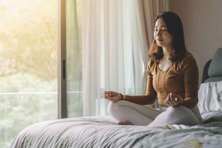 Asian woman meditating at bedroom