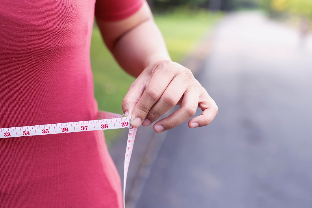 Woman measuring her waist after weight loss surgery