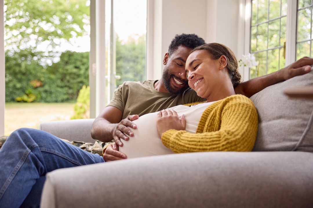 Expectant Parents sitting on couch and smiling