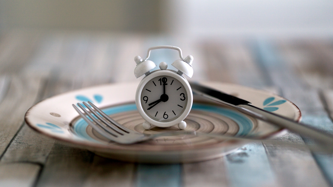 Table clock and fork on empty plate