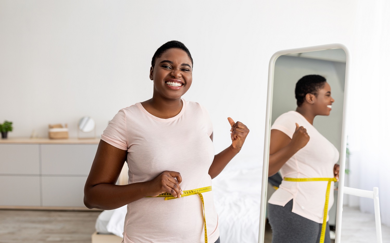 Woman measuring waist in front of a mirror