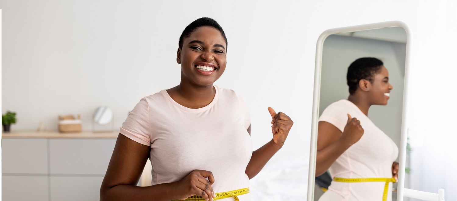 Woman measuring waist in front of a mirror