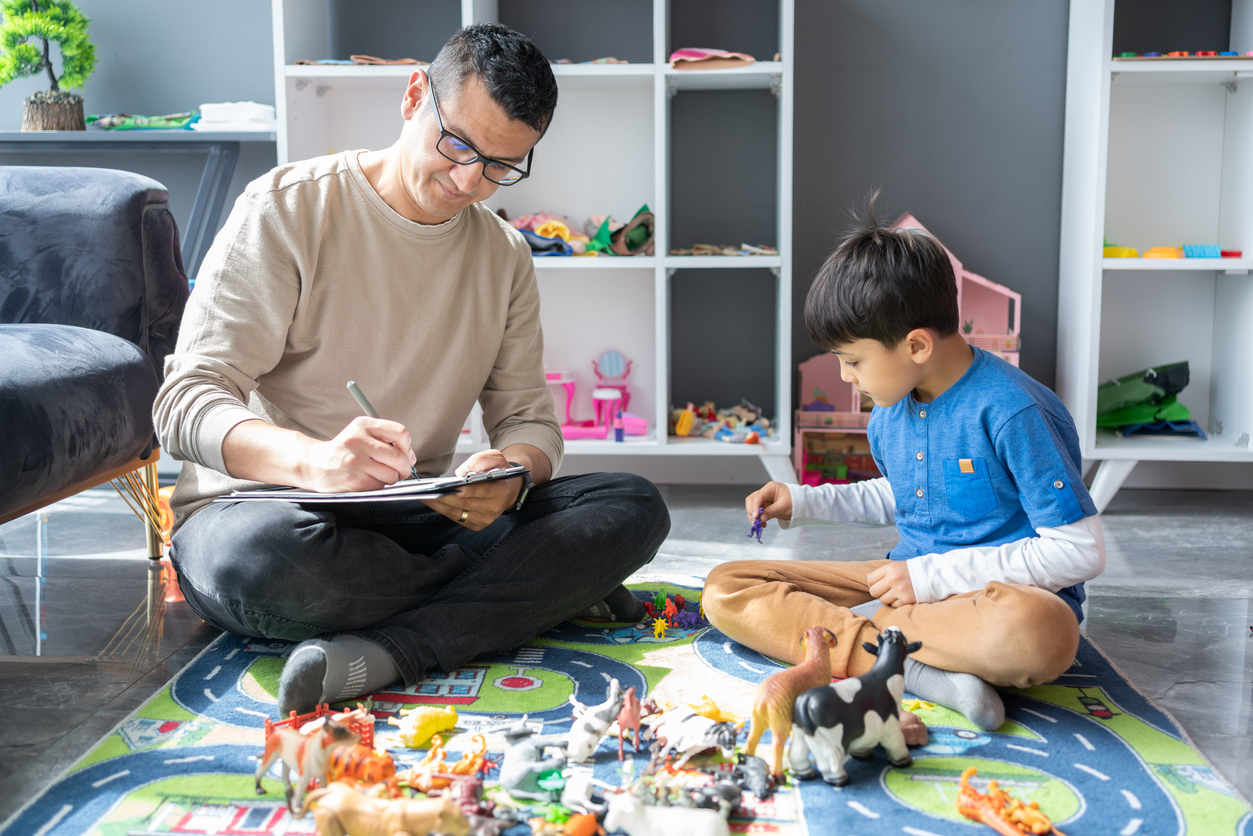 Young man taking notes while playing with Doctor