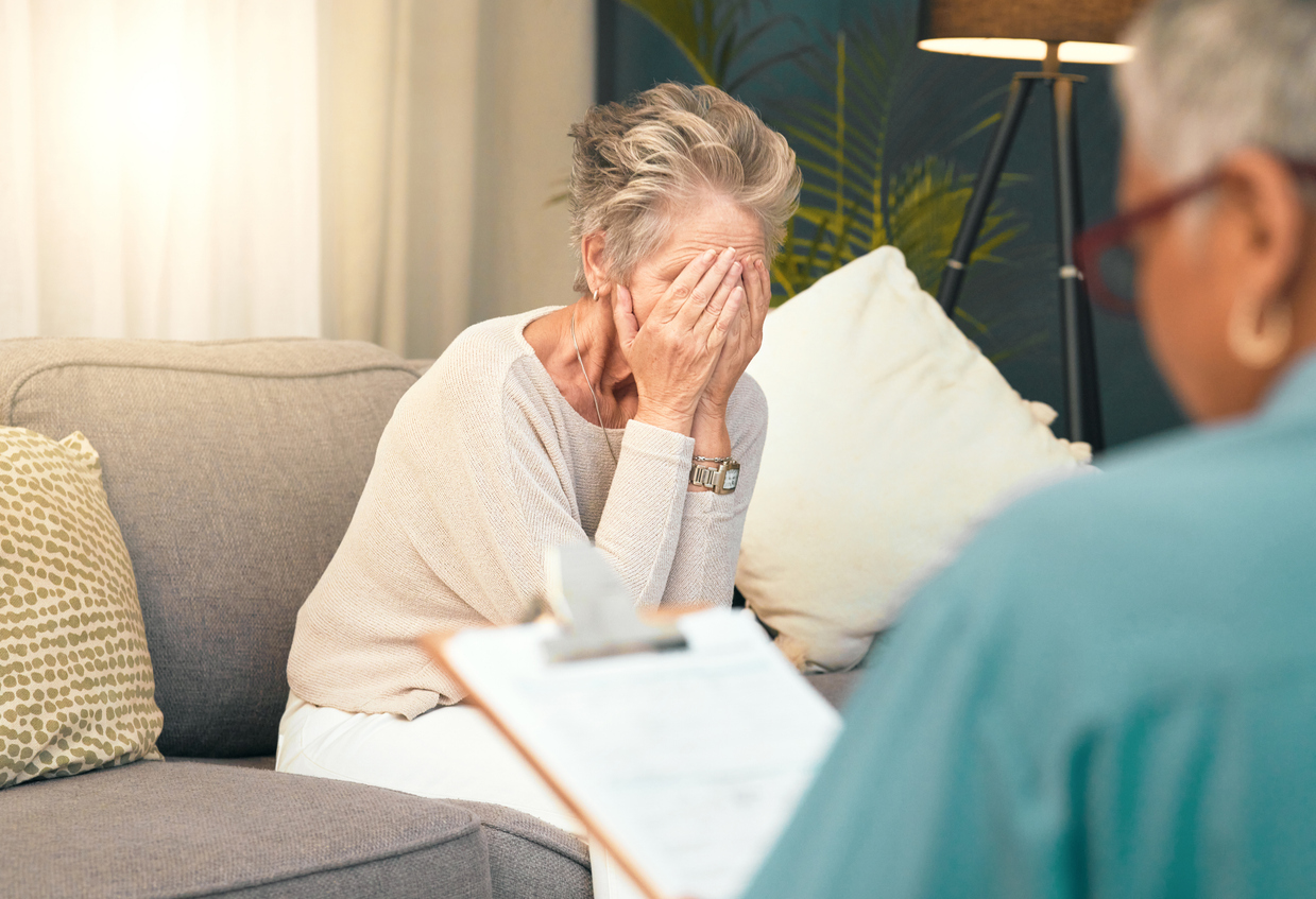 Patient covering their face with hands and talking to therapist 