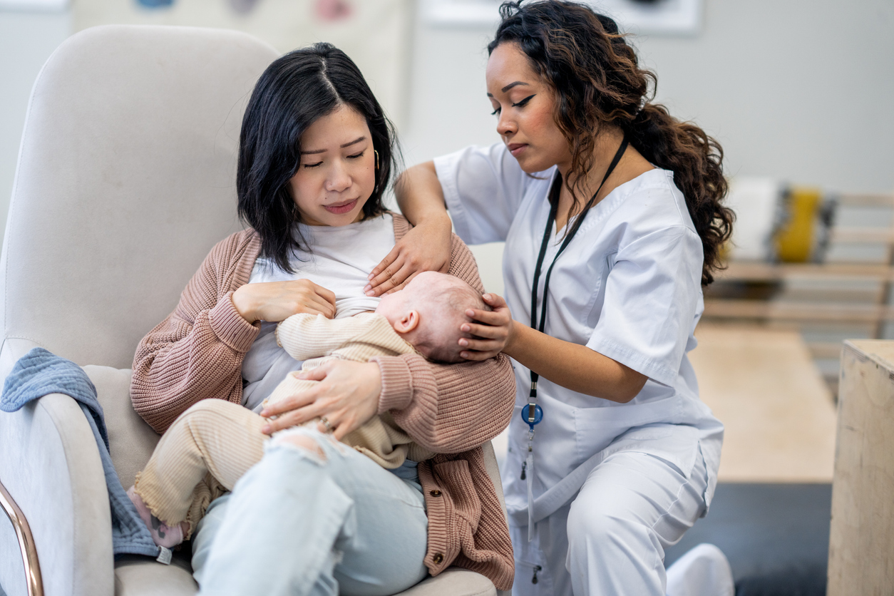 Nurse helping woman breastfeed the new born