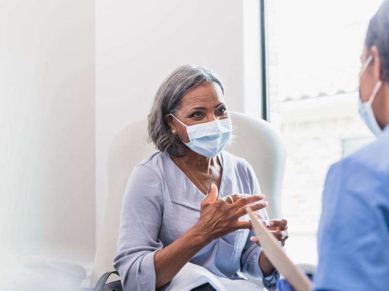 woman wearing a medical mask talk to a physicians in a medical office