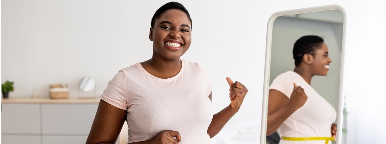 Woman measuring waist in front of a mirror