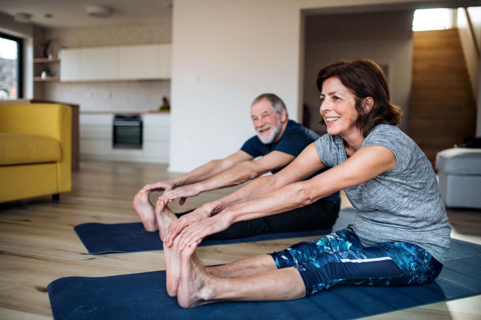 man and woman stretching on yoga mats indoors