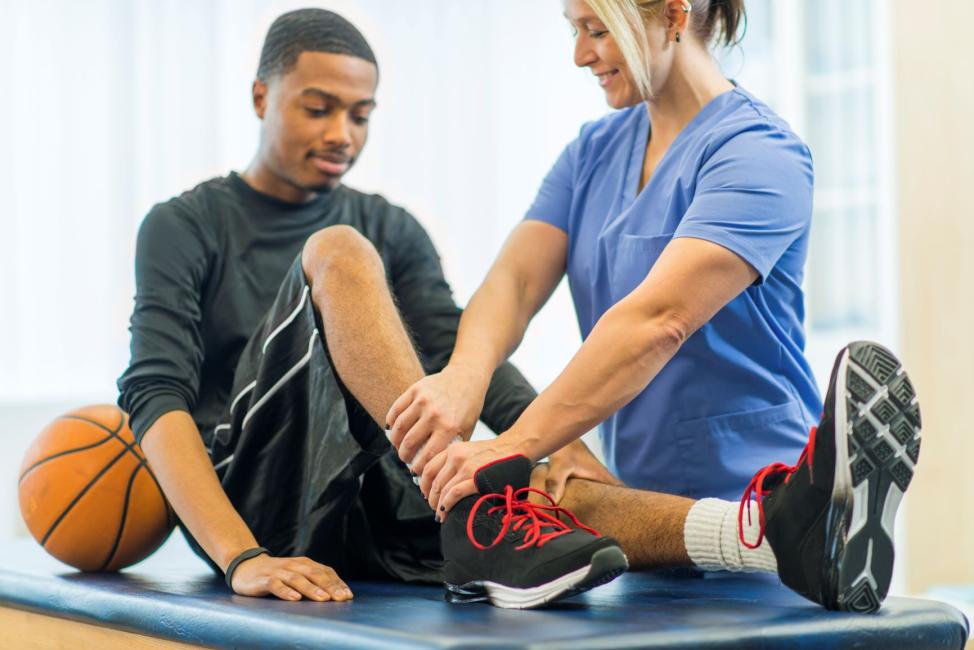 physician and male basketball player examining ankle