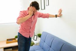 Man holding head and taking wall support