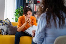 Young boy sitting on a couch talking to psychiatrist