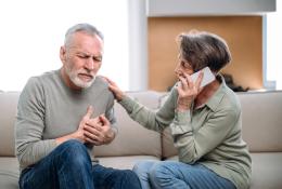 Elder couple sitting on couch. Man experiencing heart pain.