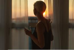 Woman looking at sunset from window