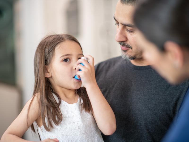 Young girl with Asthma issues using breathing inhaler