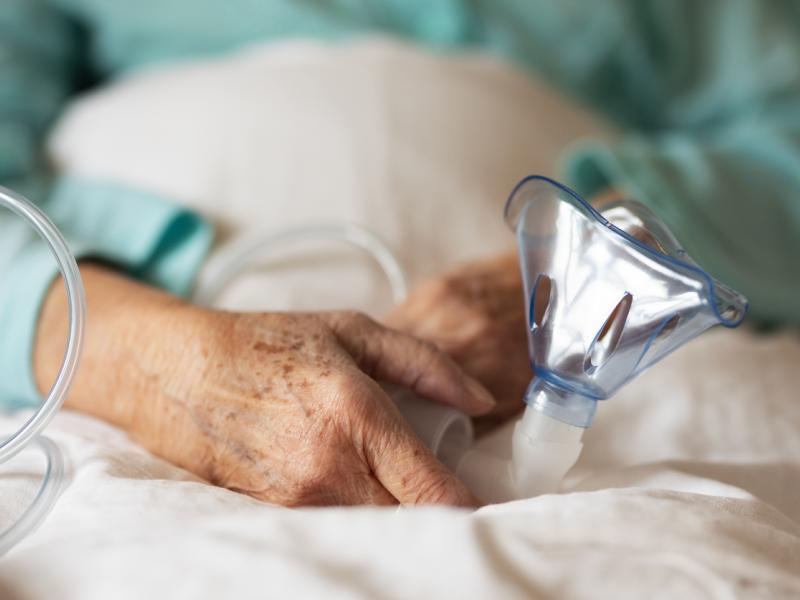 Old woman holding oxygen mask in hand 